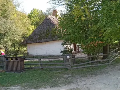 Kryta strzechą chata w skansenie wśród drzew