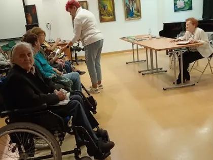 Mieszkańcy na wózkach na spotkaniu w galerii z obrazami