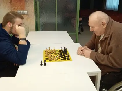 Młody mężczyzna i starszy mężczyzna na wózku grają w szachy