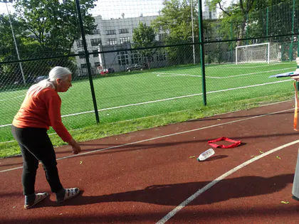 Mieszkanka podnosi szarfę na boisku podczas gier