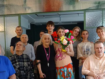 Grupa mieszkańców i uczniów pozuje do zdjęcia z bukietami kwiatów z krepiny