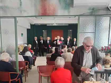 Mieszkaniec nalewa wodę, w tle koncert chóru