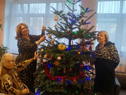 Pracownice i mieszkanka dekorują choinkę w holu