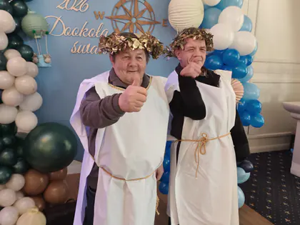 Dwaj mieszkańcy w togach i wieńcach pokazują kciuki w górę przy balonach