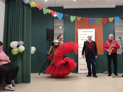 Tancerka w czerwonej sukni tańczy na scenie z saksofonistą