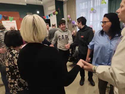 Mieszkańcy, młodzież i pracownicy tańczą w kole trzymając się za ręce