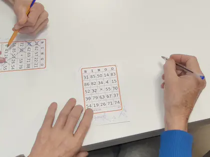 Dłonie skreślają liczby na kartach do bingo