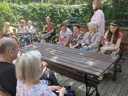 Prowadząca śpiewa z mieszkańcami w ogrodzie