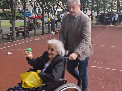 Mężczyzna pcha wózek z mieszkanką rzucającą piłkę na boisku