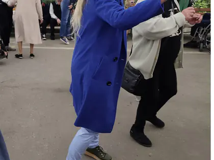 Mieszkanka w niebieskim płaszczu tańczy pod namiotem