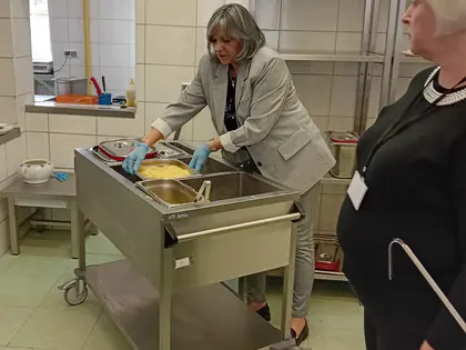 Kuchnia i dwie panie podające posiłek