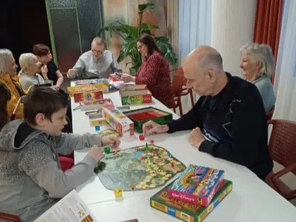 Mieszkańcy i dzieci grają w gry planszowe przy długim stole
