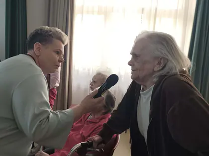 Opiekunka podaje mikrofon starszemu mieszkańcowi