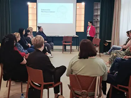 Uczestnicy szkolenia siedzą w kręgu przed ekranem